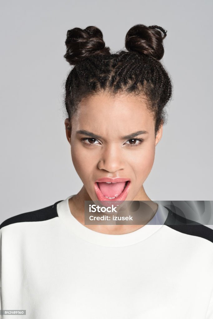Displeased afro american teenager woman screaming Studio portrait of angry afro american teenage woman screaming at camera. Studio shot, grey background. Human Face Stock Photo