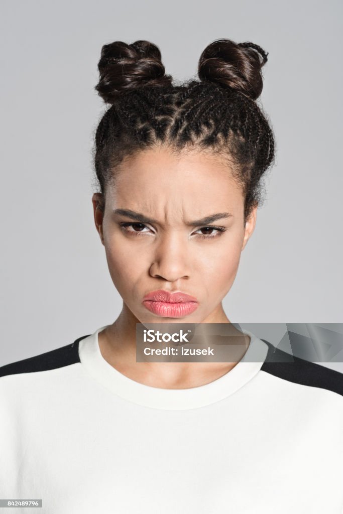 Angry afro american teenager girl Studio portrait of angry afro american teenage woman looking at camera. Studio shot, grey background. 16-17 Years Stock Photo