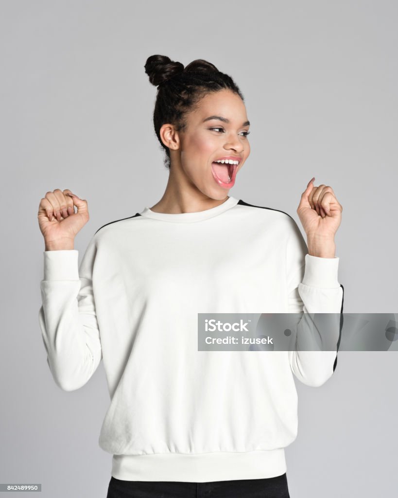 Happy afro american teenager girl Studio portrait of happy afro american teenage woman raising fists and laughing. Studio shot, grey background. Studio Shot Stock Photo