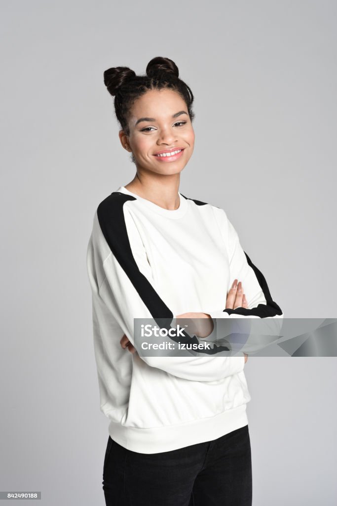 Happy afro american cute teen girl Studio portrait of smiling afro american teen female student standing with arms crossed. Studio shot, grey background. Teenager Stock Photo