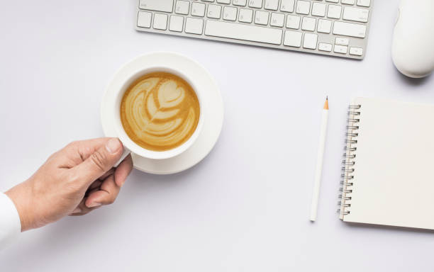 istock Male hand holding coffee cup on white modern working table. 842490498