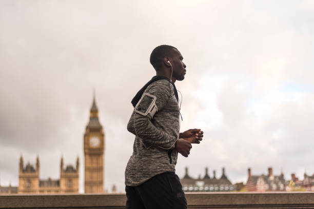 Young black man running outdoors Active young African American man jogging in London britain british audio stock pictures, royalty-free photos & images