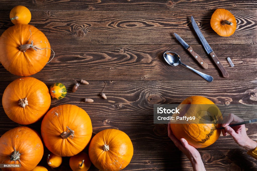 Ripe yellow pumpkins over wooden background Hands carving jack-o-latern from pumpkin over wooden background, top view, flat lay Pumpkin Stock Photo