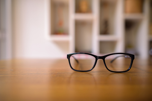 Eyeglasses laying on top of wooden table at home horizontal shot