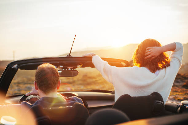 istock Happy couple looking at sunset from convertible 842605518