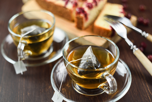 Té verde preparado en bolsitas de té de la pirámide en tazas de cristal y pie de berry. Bebida saludable photo