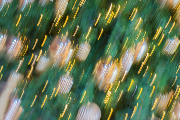 Christmas very blurred holiday abstract background. Blurred christmas balls ornaments on tree, golden lights. Selective focus. Winter holiday, Happy New Year, xmas themes