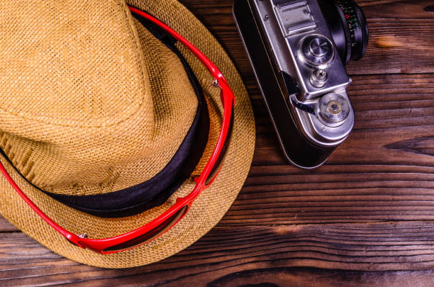istock Old rangefinder camera, sunglasses and hat on a wooden table. Top view 842617446