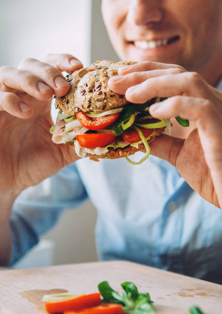 istock Man eats a big sandwich with meat and wegetables 842626018