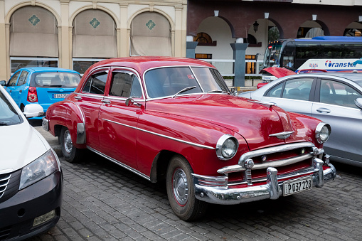 Vintage cars are parking on the street. Incidental people on the background.