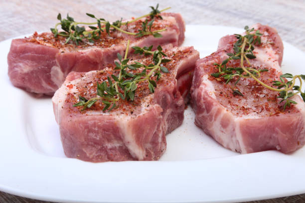 istock Raw pork chops, spices and rosemary on cutting board. Ready for cooking. 842660018