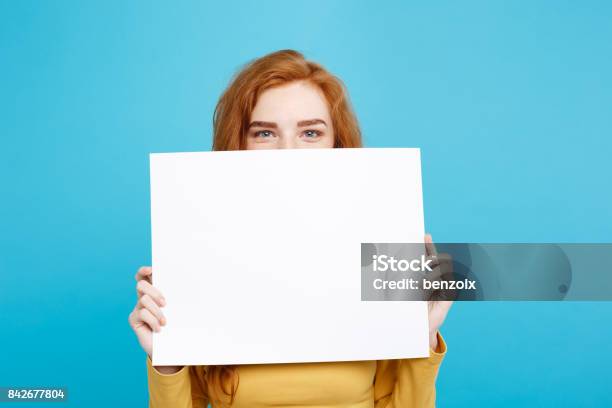 Foto de Closeup Garota Jovem Bonita Atraente Ruivos De Retrato Sorrindo Mostrando Sinal Em Branco Fundo Azul Pastel Copie O Espaço e mais fotos de stock de Segurar