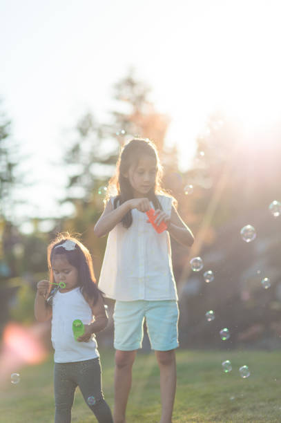 istock Sisters playfully blow bubbles outdoors at dusk 842678380