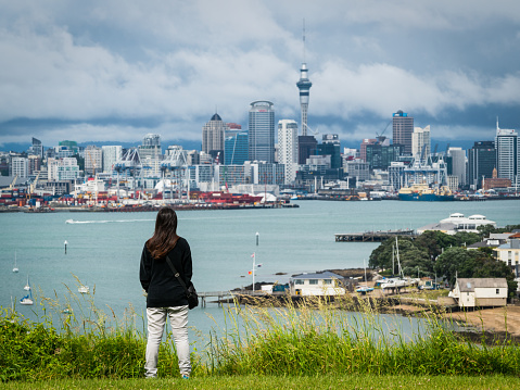 Young woman looking at Auckland city skyline of city center and Auckland Sky Tower in New Zealand.