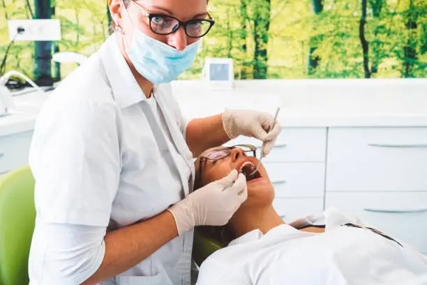 Young woman at dental exam, in a new brightly lit dentist's office, smiling and not afraid of the exam, taking care of her body, making sure teeths are in good condition, teeth whitening, female dentist