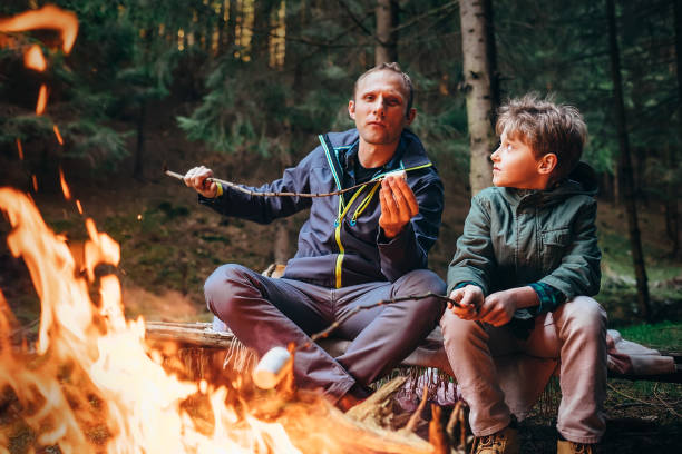 istock Picnic in forest - father and son roste marshmallow on campfire 842686628