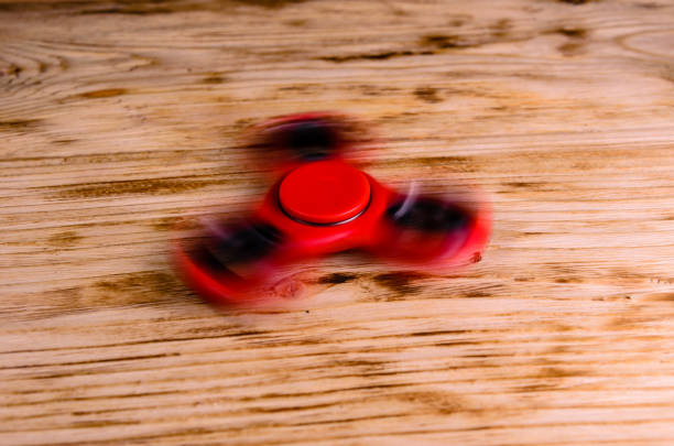 istock Red fidget spinner rotates on wooden desk 842689286