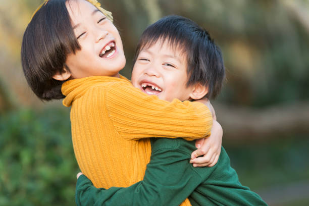 menino asiático e uma irmã, abraçando, rindo - embracing smiling gap children only - fotografias e filmes do acervo