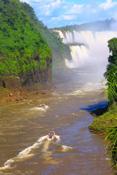 Impressive Iguacu falls and motorboat adventure tour on the Argentina side of the border, one of the most beautiful waterfalls in the world and one of the seven Wonders of Nature, dramatic beauty in nature landscape - Idyllic Devil's Throat - international border of Brazilian Foz do Iguacu city, Parana State, Argentina Puerto Iguazu city, Misiones province and Paraguay - rainforest landscape panorama, South America impresionantes cataratas de iguazu y safari de aventura barco de motor en el lado de argentina, frontera internacional del paisaje - garganta del diablo idílico - belleza brasileña de foz do iguacu, paraná, puerto iguazú, misiones y paraguay - américa del sur