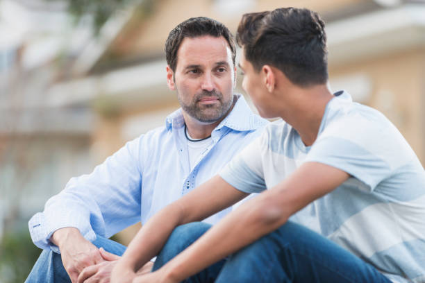 istock Father sitting with serious teenage boy 842699352