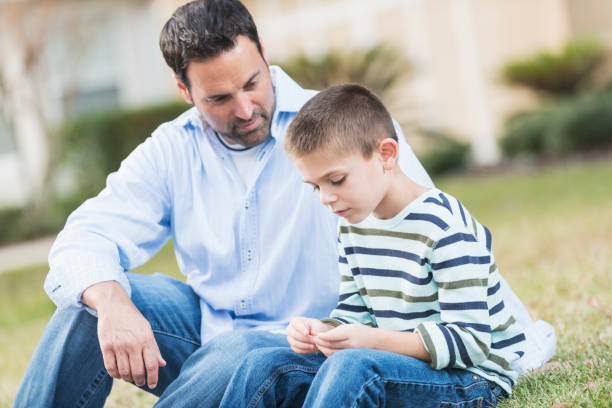 istock Father and young son sitting on lawn 842699354