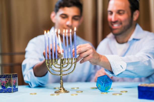 istock Father and teenage son lighting menorah 842699470