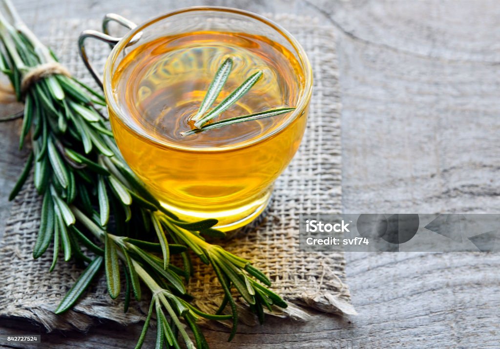 Rosemary herbal tea in a glass cup on rustic wooden background. Rosemary herbal tea in a glass cup on rustic wooden background.Selective focus. Tea - Hot Drink Stock Photo