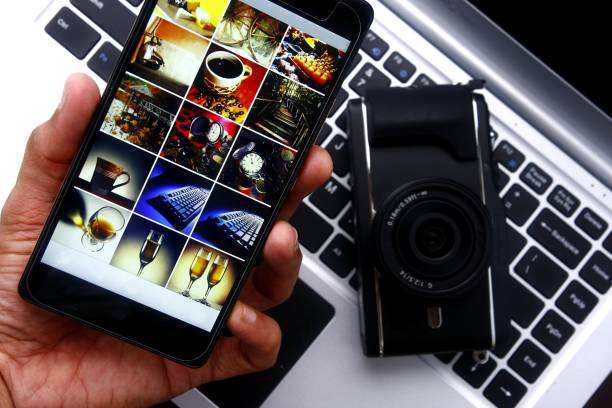 hand mit einem smartphone über einen digitalen spiegellose kamera und laptop-computer - smartphone fotos stock-fotos und bilder
