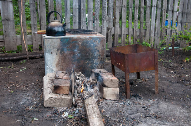 istock hiking kitchen for a shish kebab. brazier, bricks, bonfire, coals, kettle on the background of an old wooden fence 842744422