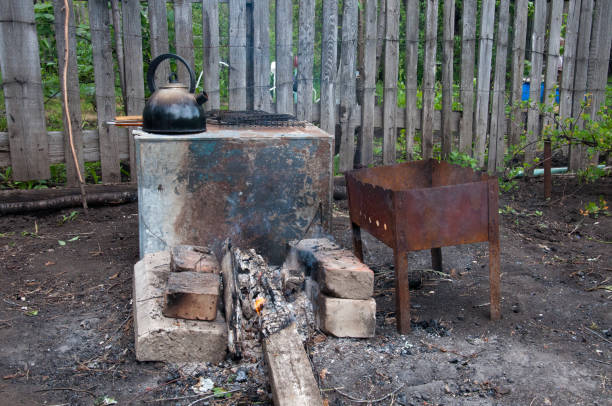 istock hiking kitchen for a shish kebab. brazier, bricks, bonfire, coals, kettle on the background of an old wooden fence 842744528