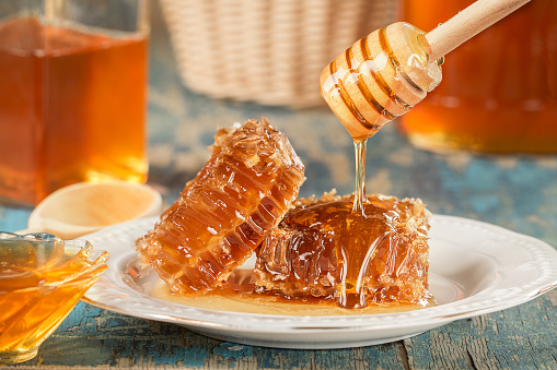 Sweet honeycomb and wooden Honey dripping. Honey dipper