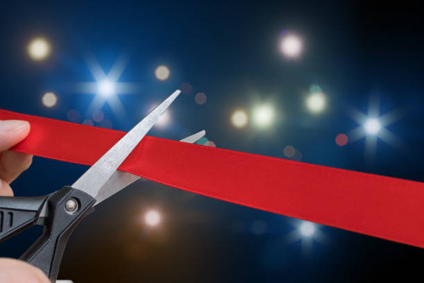 scissors are cutting red ribbon or tape. flashing lights in background. - opening ceremony flash imagens e fotografias de stock