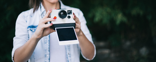 Woman holding old polaroid camera with photo, horizontal, free space