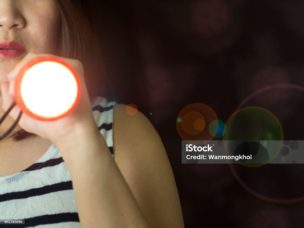 Part of Asian woman holding flashlight on left hand peeking the door in the dark Flashlight Stock Photo