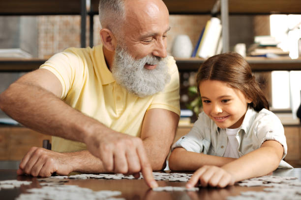 istock Adorable little girl assembling jigsaw puzzle with her grandfather 842781182