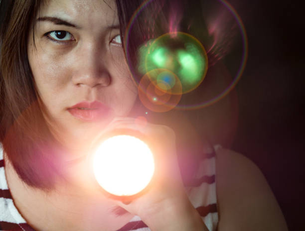 istock A woman holding flashlight in her hand, looking forward and seeking something, shining lights in the mystery dark, feeling scare and fear, Halloween, ghost, horror theme 842781458