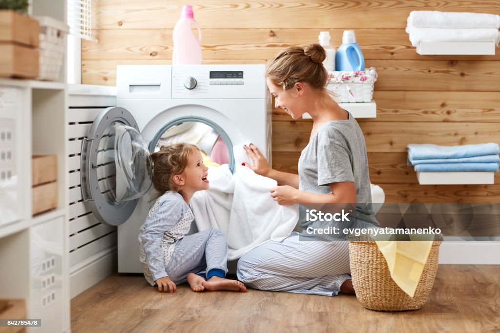 Femme au foyer mère de famille heureuse et l’enfant dans la buanderie avec machine à laver - Photo de Lessive - Corvée domestique libre de droits