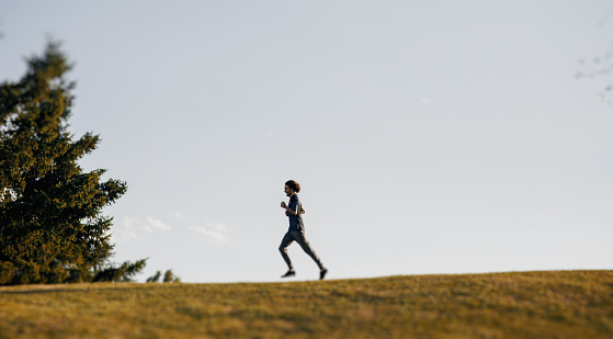 Distant view of a man jogging on a hill outdoors.