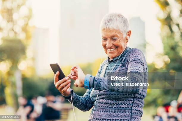 Senior Sportswoman Using A Smart Phone And A Smart Watch Stock Photo - Download Image Now