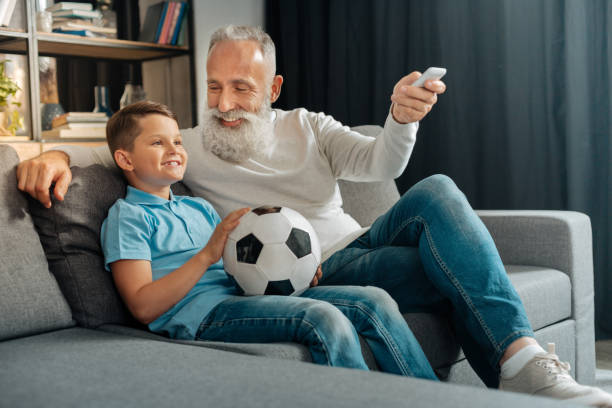 istock Man turning air conditioning on while watching football with grandson 842793410