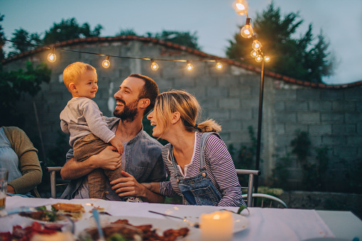 Photo of a little boy celebrating his birthday on an outdoors dinner party with his family