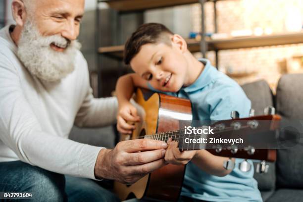 Smiling Grandfather Showing Grandson How To Play Guitar Stock Photo - Download Image Now