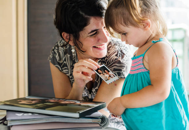 Mother and daughter spending time together Mother and daughter looking photo album together family photos album stock pictures, royalty-free photos & images