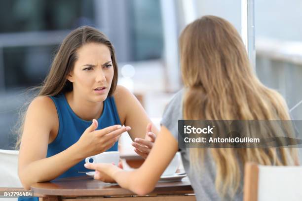 Photo libre de droit de Deux Jeunes Filles Parler Sérieusement Dans Un Coffee Shop banque d'images et plus d'images libres de droit de Femmes