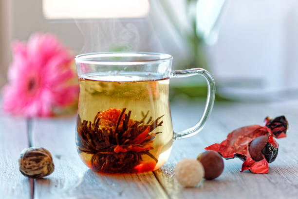 中国緑茶の花芽がガラスのティーカップに咲きます。朝の朝食。浅い被写し界深度 - tea chinese tea heat teapot ストックフォトと画像