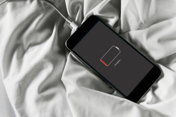 Closeup of dead mobile phone charging lying on white fabric background
