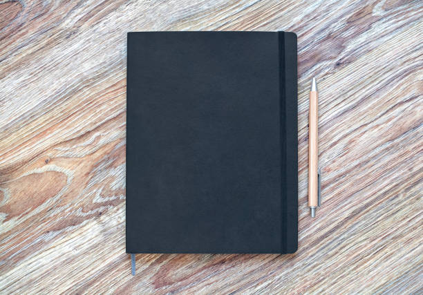 Closed planner with pen is on a wooden desk.