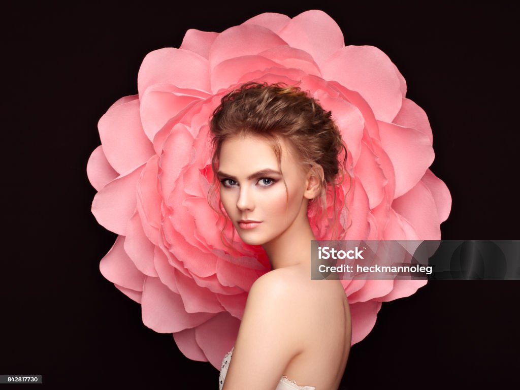 Beautiful woman on the background of a large flower Beautiful woman on the background of a large flower. Beauty summer model girl with pink peony. Young woman with elegant hairstyle and makeup. Fashion photo Women Stock Photo