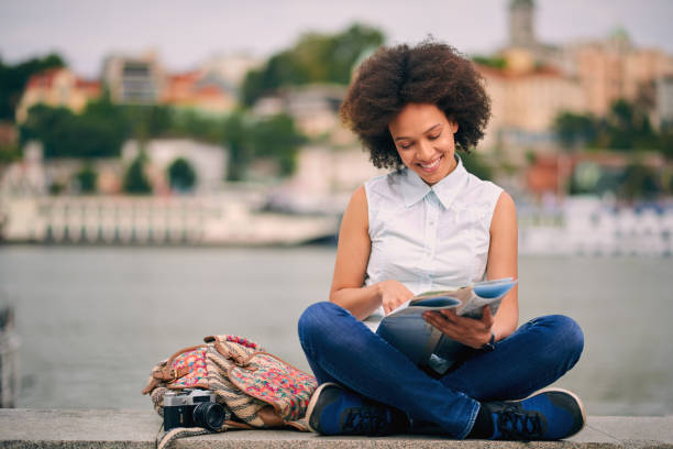 istock Mixed race tourist sitting on dock and looking at map 842817900