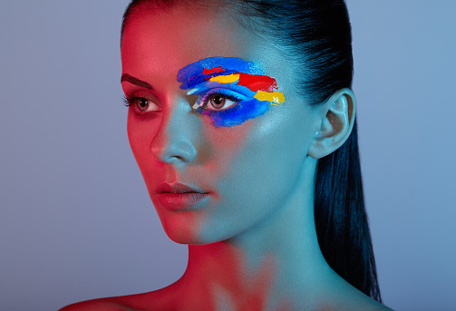 Fashion model woman with colored face painted. Beauty fashion art portrait of beautiful woman with colorful abstract makeup. Face painted paints. Multicolor design